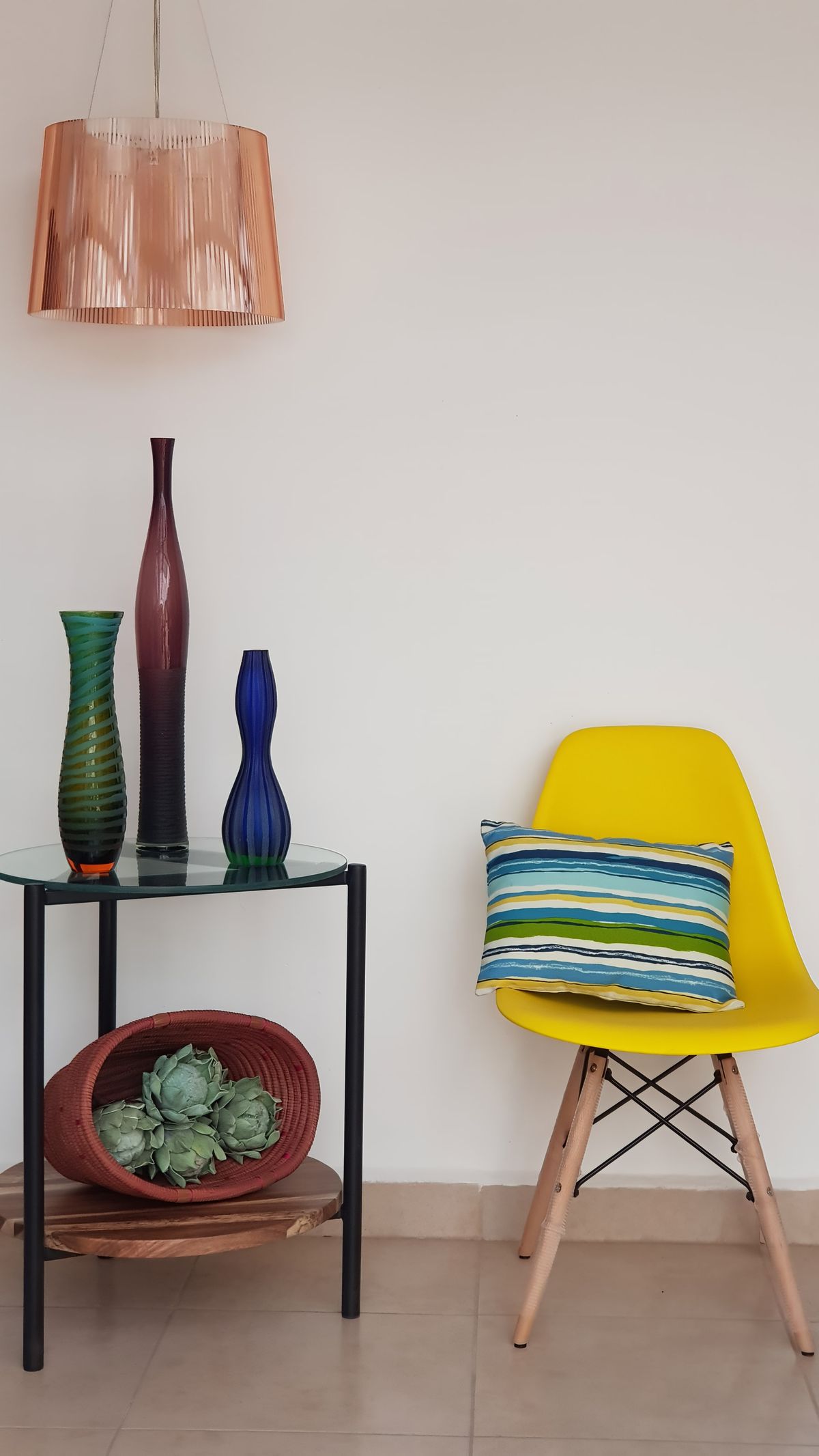 Detalle con jarrones de vidrio de colores y silla amarilla