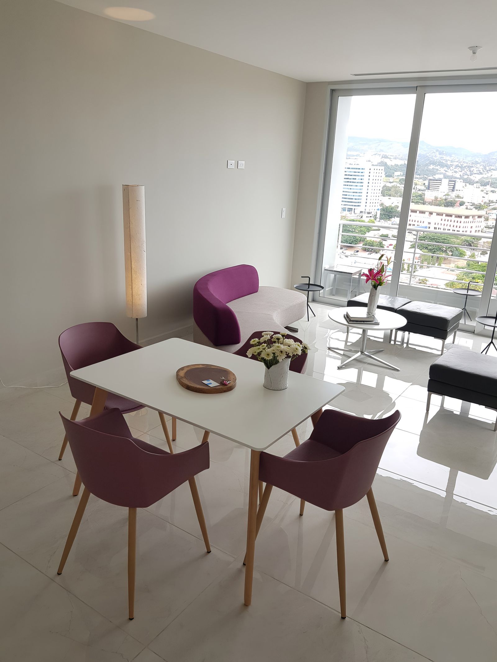 Comedor con mesa blanca, sillas malva y ventanal luminoso