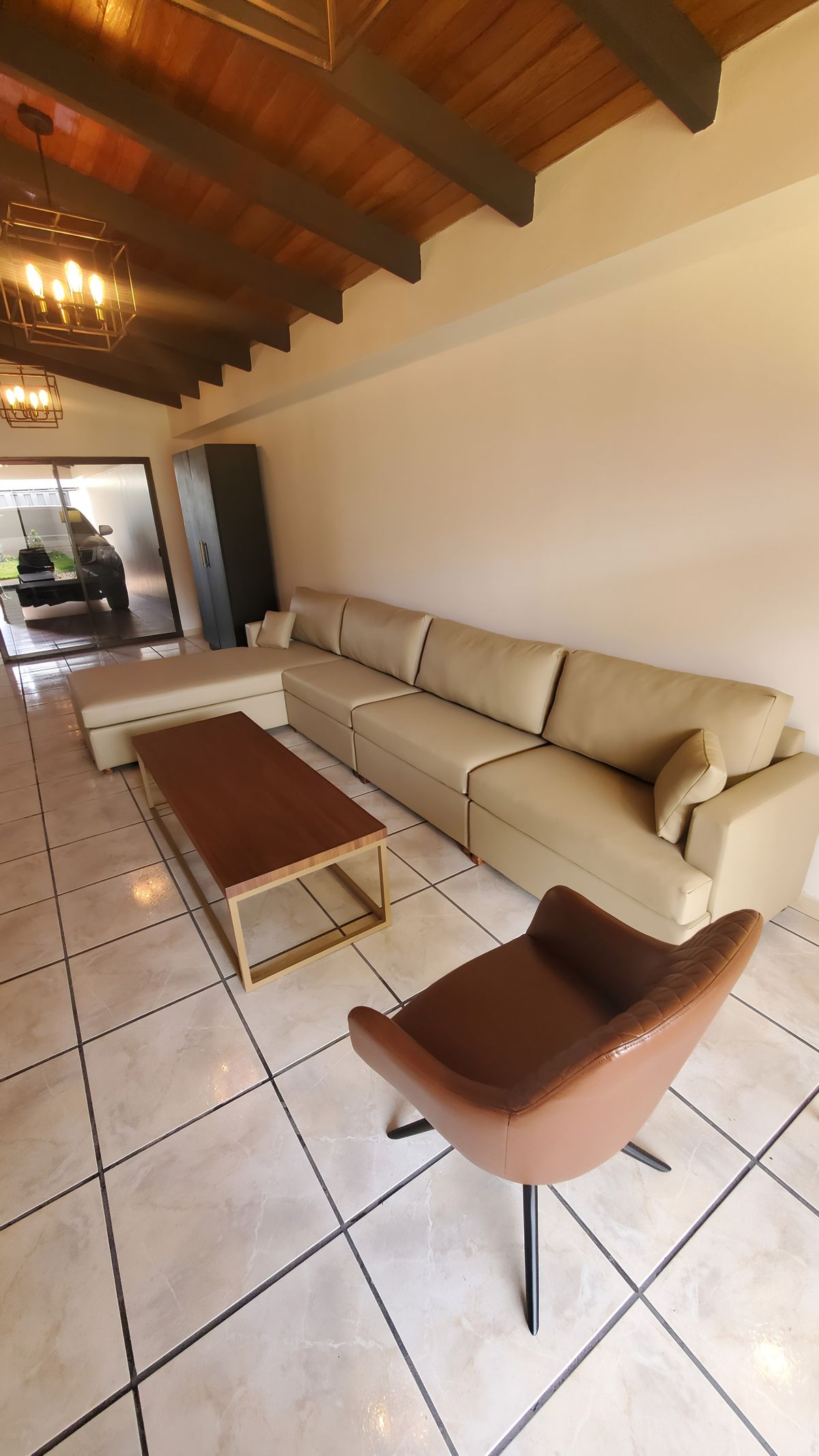 Sala bajo techo de madera con sofás de cuero y sillón café