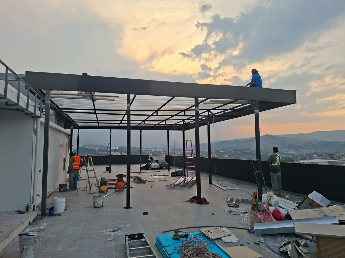 Obra gris con pérgola metálica al atardecer sobre la ciudad